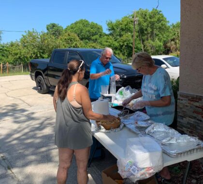volunteers serving meal to person attending community cookout at homeless center